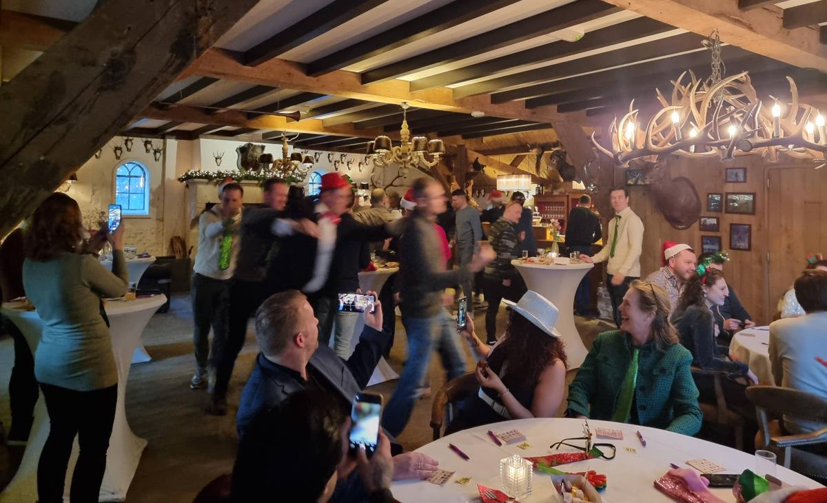 Collega’s spelen de Kerstbingo van BedrijfsuitjeQuiz.nl – feestelijk teamuitje op locatie vol humor, muziek en kerstaccessoires.